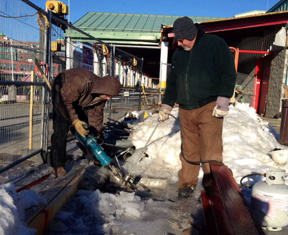 Brian Trafford, left, and Jason Thibeault, who work for Northeast Contractors, use a blow torch and a jackhammer to melt the ice and remove a metal plate during renovations of the Casco Bay Lines terminal.