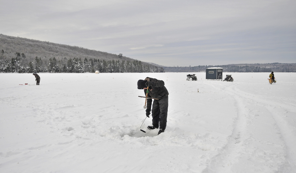 Staff photo by Michael G. Seamans COLD TRAP: Jeremny Bessey, 19, of Canaan, clears his fishing hole of ice while ice fishing at Lake George Regional Park on the Canaan and Skowhegan town line on Saturday. Bessey arrived at 5am to fish with no bites as of noon. "It was 20 below zero when I got here. So at least it has warmed up to 1 degrees." Said Bessey.