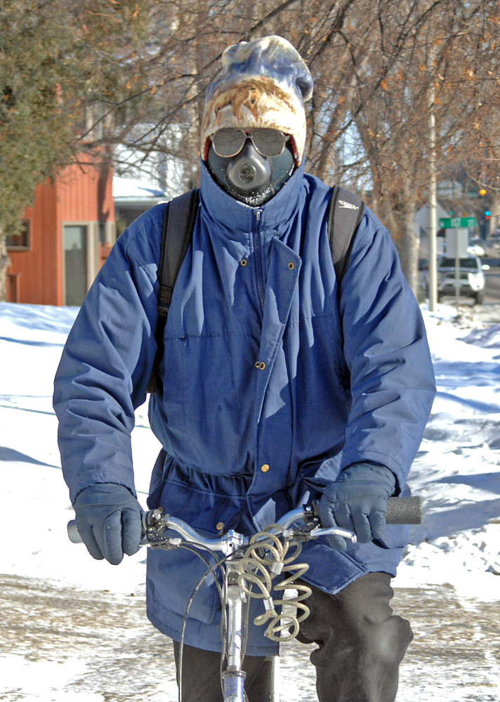 Jon Kramer, of Bismarck, N.D., said a good way to beat the cold conditions is with a face mask called the cold avenger. Kramer uses the unusual looking face mask to break the wind as he rides his bicycle on Monday.