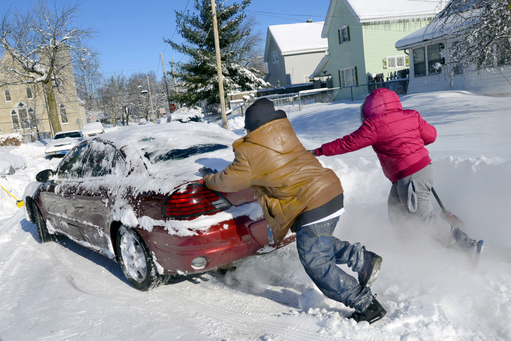 Anton Marble and his sister, Tamika, help their mother, Jaina McGee, free her car from the snow in Marion, Ind., on Tuesday, Jan. 7, 2014. More than 13 inches of snow fell on the area as temperatures plunged to a record 14 below zero Monday night.
