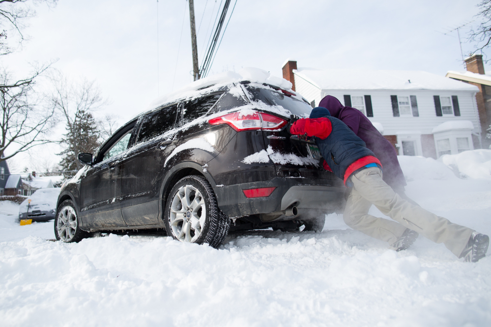 Will King, 14, tries to push an SUV driven by his father Bob up their driveway in Ann Arbor, Mich., on Monday.