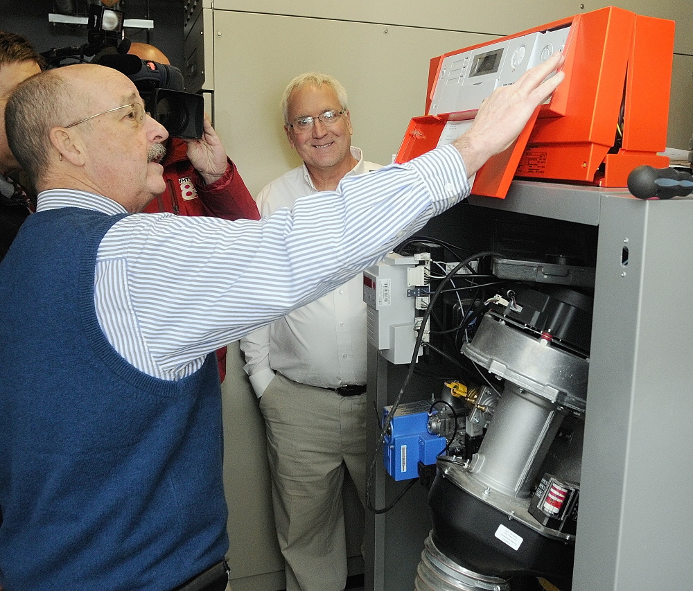 NATURAL GAS: City Manager William Bridgeo, left, flips the switch on the new natural gas fired boiler on Tuesday at the boiler room in the basement of Augusta’s City Center. Jim Bolduc, a sales manager at Viessman, the company that made the boiler, center, watches the ceremonial switch flipping.