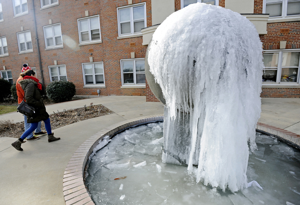 Students walk past a frozen fountain at Troy University in Troy, Ala., on Tuesday.