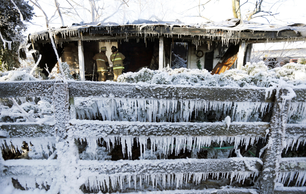 Lexington Fire Department Maj. Joe Madden, left, and firefighter Casey Wiley, look for hotspots at the scene of an overnight house fire in Lexington, Ky., Tuesday. Firefighters had to battle the fire in sub-zero temperatures.