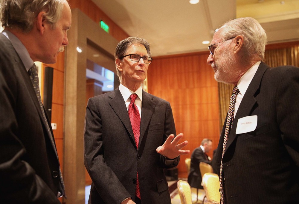 Boston Red Sox owner John Henry, center, speaks with Robert Gallery, left, of Bank of America, left, and Barry White, during a Greater Boston Chamber of Commerce breakfast meeting at the Mandarin Oriental Hotel in Boston, Wednesday, Jan. 8 2014. Henry, who recently purchased The Boston Globe, said Wednesday at the breakfast that the newspaper would work to remain “aggressively relevant” in the changing media environment.