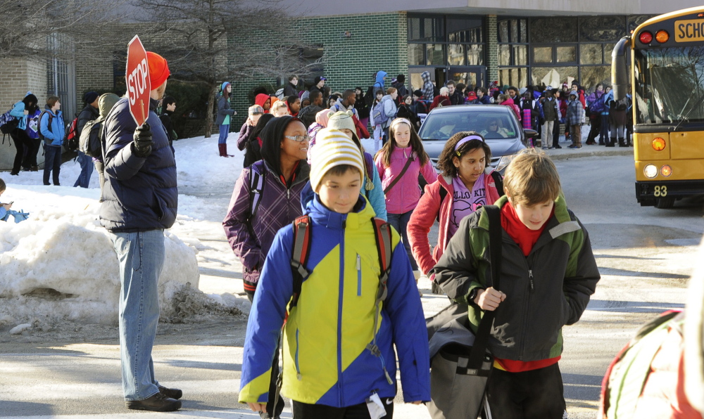 Crossing guide Adam Waxman, left, assists students leaving King Middle School in Portland on Wednesday.
