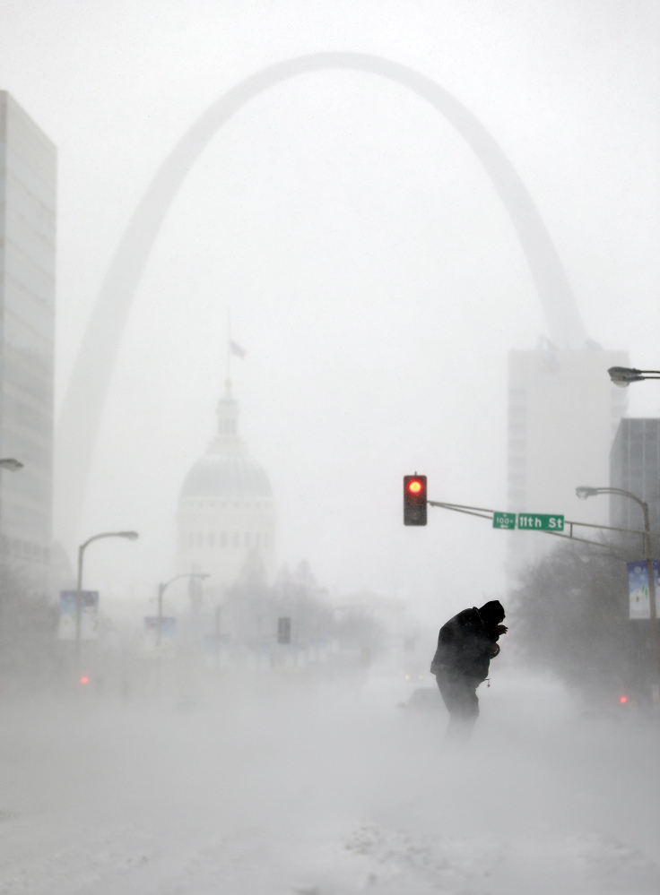 A person struggles to cross a street in St. Louis in blowing and falling snow on Sunday. Experts dismiss global warming skeptics who point to cold snaps as disproving climate change.