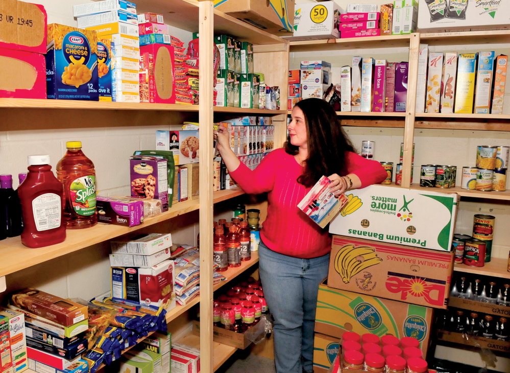 WELCOME: Jennifer Johnson stocks shelves in the recently opened food pantry at the Waterville’s George J. Mitchell School, where 72 percent of children get free or reduced lunches.