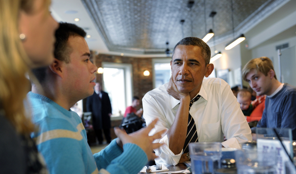 President Barack Obama listens to Andres Cruz, second from left, as he has lunch with five young people at The Coupe restaurant in the Columbia Heights section of Washington on Friday. The five are spearheading creative outreach efforts to connect with and help enroll young consumers in the new health care marketplaces. Seated at the table with Obama at left is Anne Johnson.