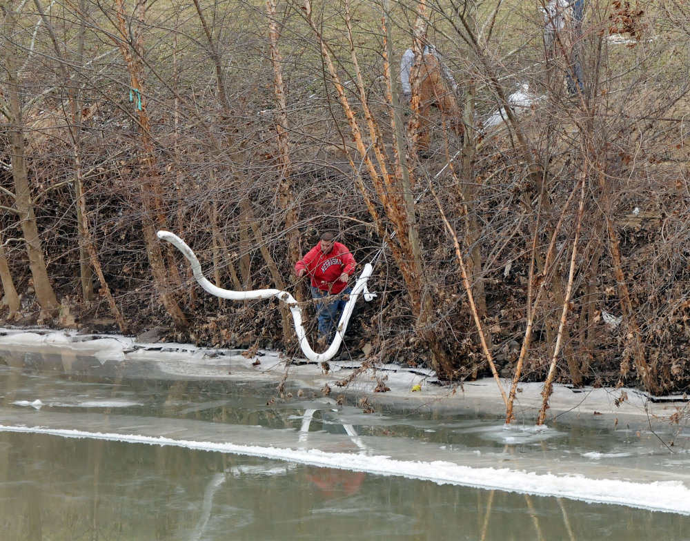A Freedom Industries worker places a boom in the Elk River on Thursday at the site of a chemical leak in Charleston that has fouled the drinking water in five West Virginia counties.