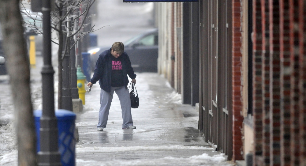 keeping balance: A woman tries negotiate the ice-covered sidewalk on Main Street in downtown Waterville on Saturday.
