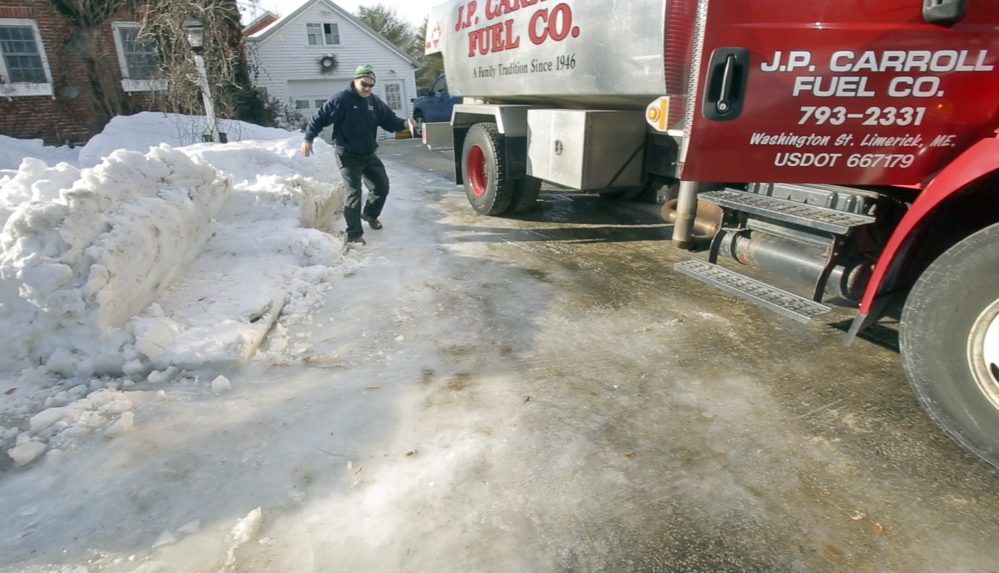 Jim Carroll of J.P. Carroll Fuel Co. slips down an icy driveway while making an oil delivery in Limerick on Tuesday. Carroll is one of four siblings running the company started by their grandfather. In a time of mega-utility mergers, oil delivery remains a family-centered business in Maine.