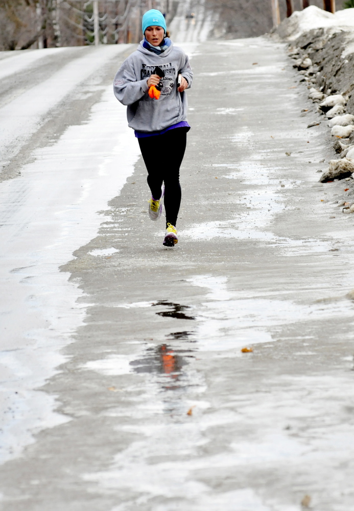 Staff photo by David Leaming SLOPPY RUN: Lindsey Welch runs through slush, water and ice in Waterville on Sunday, Jan. 12, 2104. "Today is not as bad as Saturday except for my wet feet," Welch said.