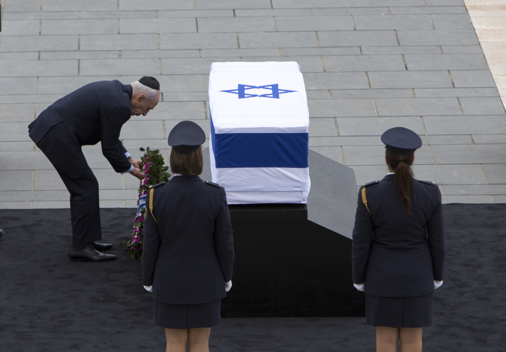 Israeli President Shimon Peres lays a wreath on the coffin of former Israeli Prime Minister Ariel Sharon at the Knesset plaza, in Jerusalem on Sunday.