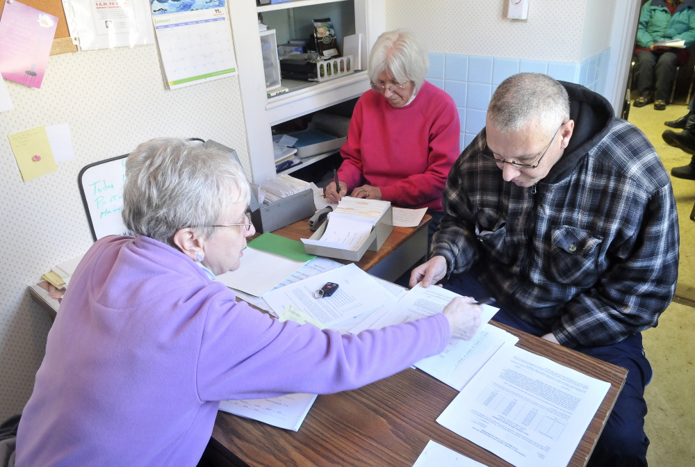 Paperwork: Pastor Joyce Perkins, left, helps Joe Lessard, 49, of Benton, fill out the proper paperwork to receive food from the First Baptist Church food pantry in Fairfield on Thursday.