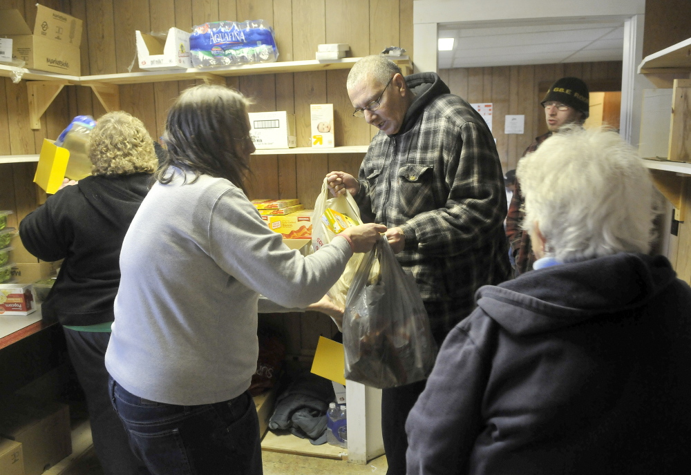 FOOD FOR FOLKS: Joe Lessard, 49, of Benton, center facing, receives bags of food from volunteers at the First Baptist Church food pantry in Fairfield on Thursday.