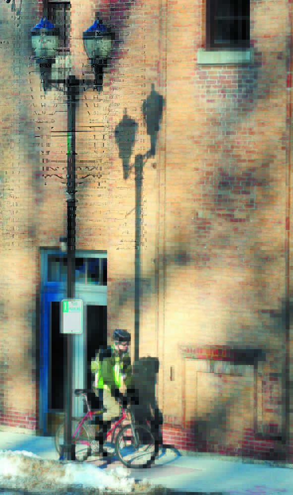 Colonial Shadows: A bicyclist pedals through a patch of late afternoon sunshine in front of the Colonial Theater in March 2012 on Water Street in downtown Augusta.