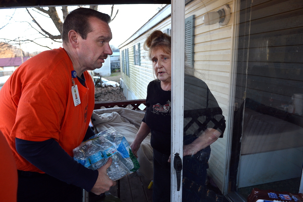 JoAnn Chapouris asks paramedic John Johnson to carry a case of water inside her home in Rand, W.Va., on Sunday.