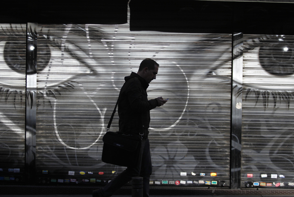 FILE - In this Thursday, Oct. 31, 2013, file photo, a man looks at his cellphone as he walks on the street in downtown Madrid. The National Security Agency has implanted software in nearly 100,000 computers around the world that allows the U.S. to conduct surveillance on those machines, The New York Times reported Tuesday.