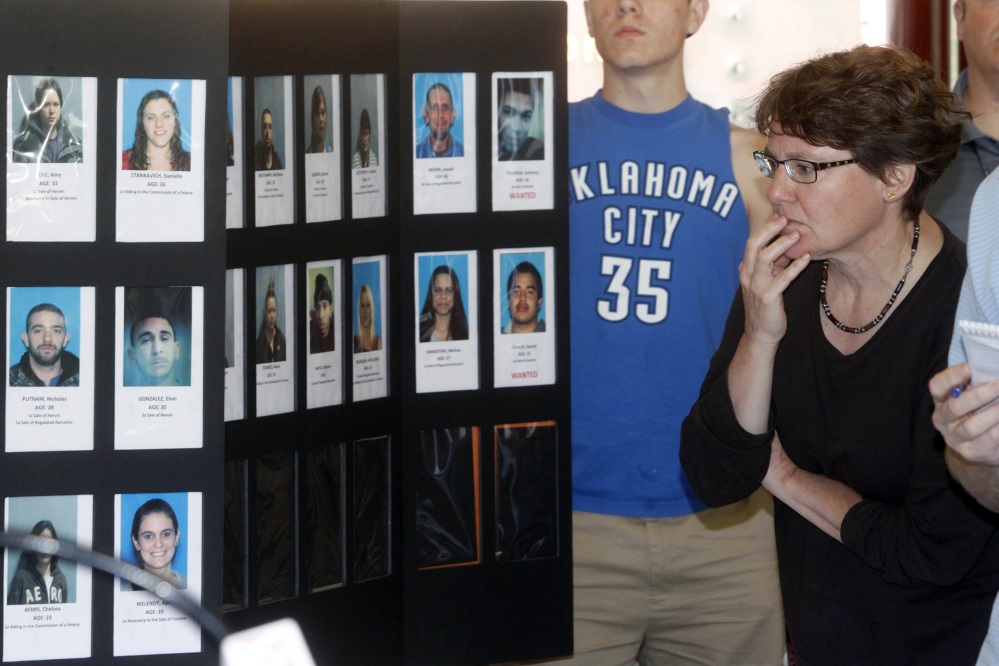 In this June 19, 2013, photo, Springfield, Vt., resident Susan White looks over booking photos displayed at a Vermont State Police news conference to discuss the arrest of 36 people as part of a large drug sweep.