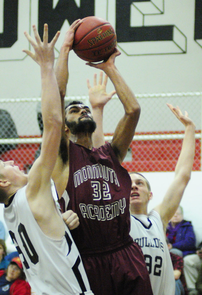 Staff photo by Joe Phelan Hall-Dale's Josh Berberich, left, and Wesley Lapointe, right, try to stop a shot by Monmouth Academy's Marcques Houston during a game on Wednesday January 15, 2014 in Hall-Dale's Penny Memorial Gym in Farmingdale.