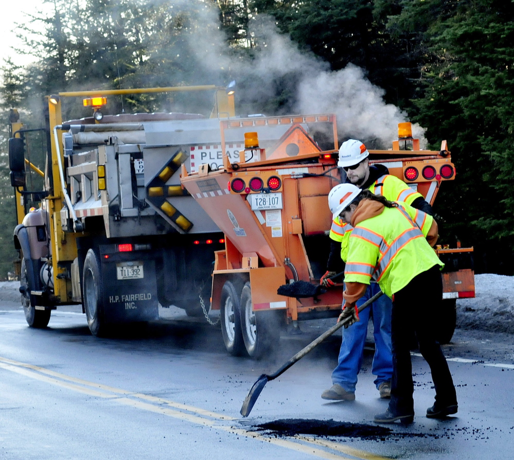 STEAMED: Steam rises from warm asphalt as Maine Department of Transportation employees Deven Moon and Tina Gilbert fill some of the numerous potholes on the Unity Road in Benton on Wednesday.