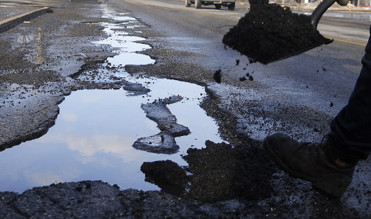 PATCH WORK: Augusta Public Works employee Dave Burlingame patches potholes Wednesday in Augusta. Recent changes in temperatures and several inches of rain caused roads across Maine to heave this week.