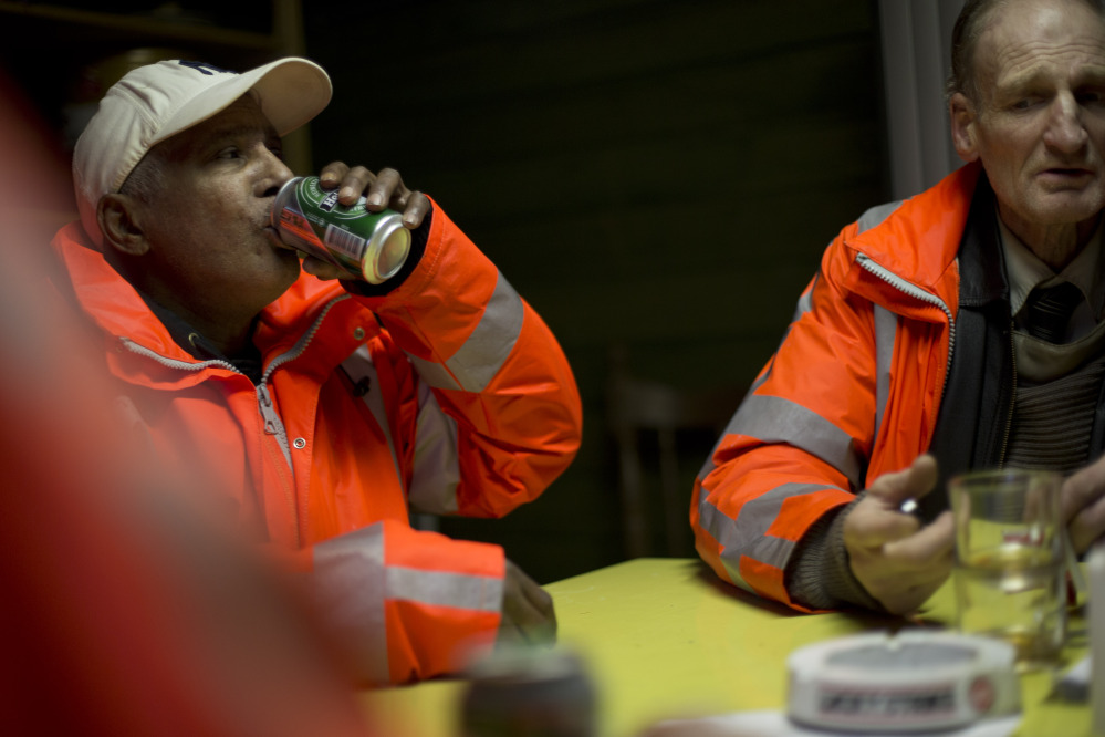 Ramon Mohamed Halim Smits, left, and Fred Schiphorst, participants in the pilot project, pause for a beer and cigarettes in their clubhouse in Amsterdam’s eastern part Wednesday.