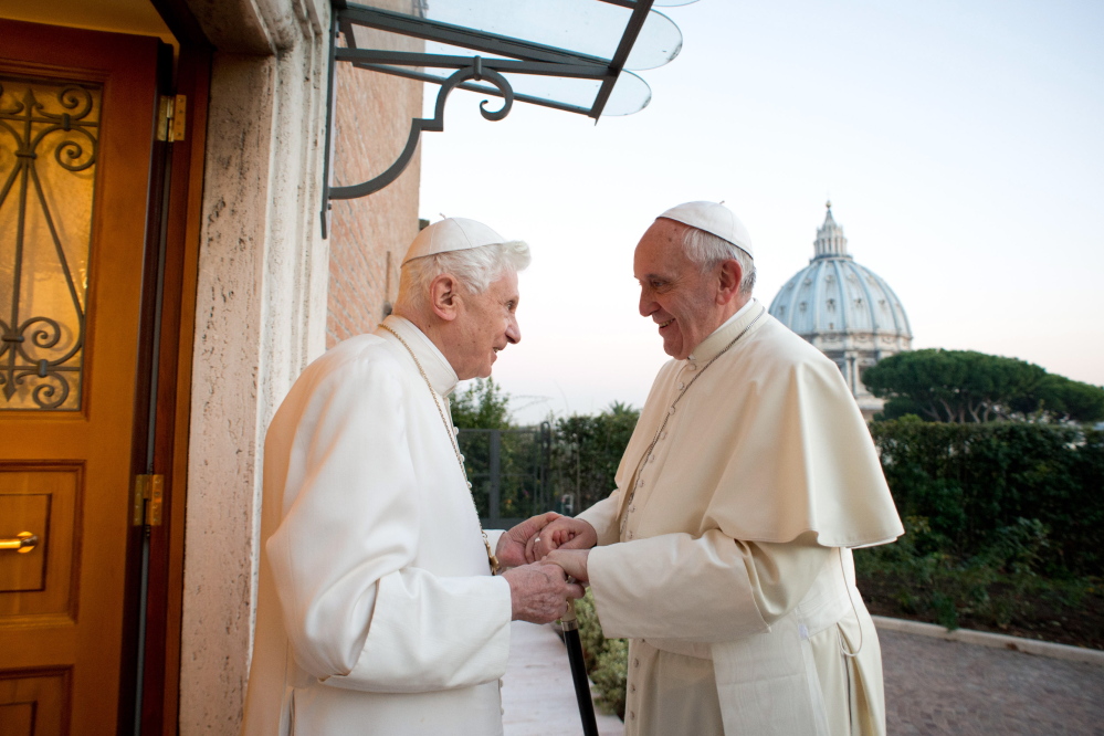 In this picture provided by the Vatican newspaper L’Osservatore Romano, Pope Emeritus Benedict XVI, left, welcomes Pope Francis as they exchanged Christmas greetings, at the Vatican on Dec. 23, 2013.