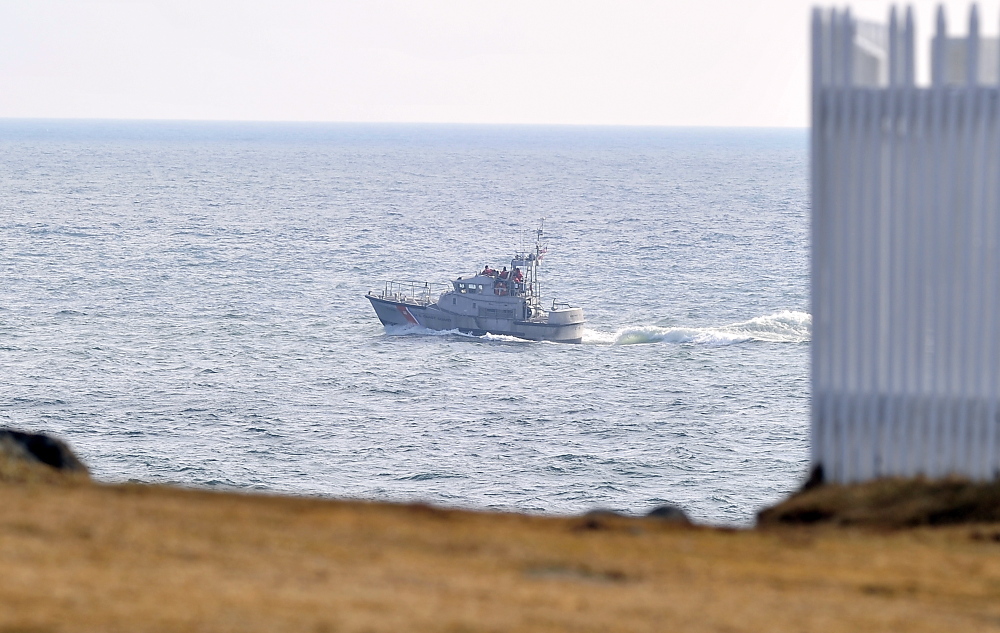 A Coast Guard boat cruises by Pemaquid Point, where searchers looked for survivors after receiving a report of a sailboat sinking.
