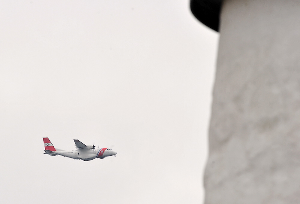 A Coast Guard plane flies by Pemaquid Point lighthouse to help search for survivors of a reported sailboat sinking Friday. The search for the vessel was suspended Friday afternoon.