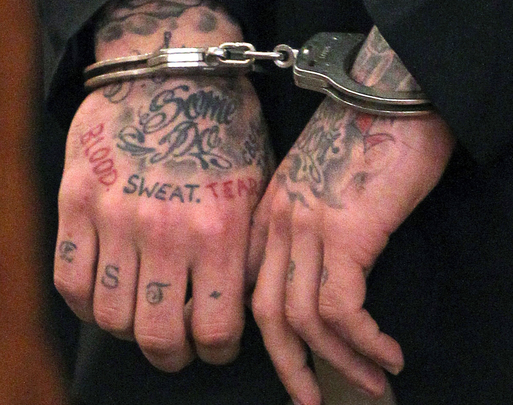 Former New England Patriots player Aaron Hernandez’s tattooed hands are secured with handcuffs in this Dec. 23, 2013, photo.