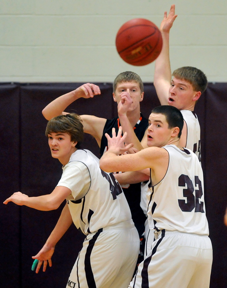 Staff photo by Michael G. Seamans Winslow High School's Justin Martin, 30, center facing, passes the ball out to teammate Justin Kervin, 15, as he is triple teamed by Maine Central Institute defenders in Pittsfield on Friday.