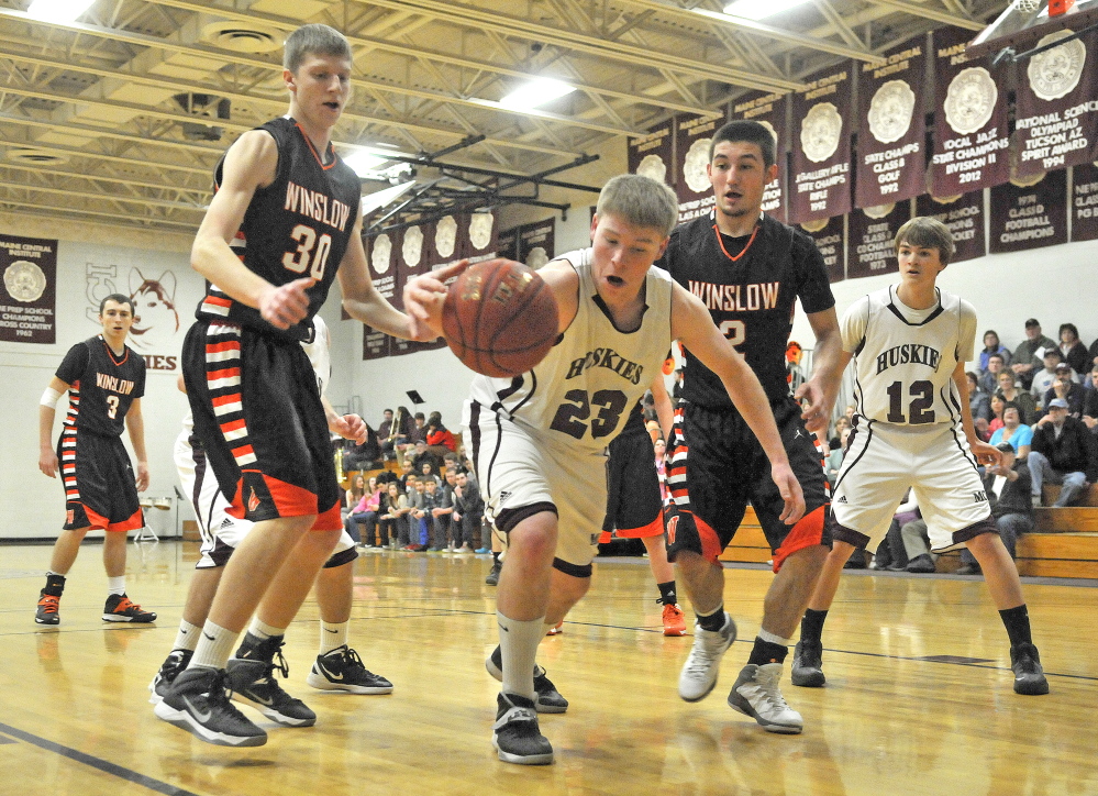 Staff photo by Michael G. Seamans Maine Central Institute's Mitchell Hallee, 23, center, fights for the loose ball with Winslow High School's Nason Lanphier, 2, right, and Justin Martin, 30, left, in Pittsfield on Friday.