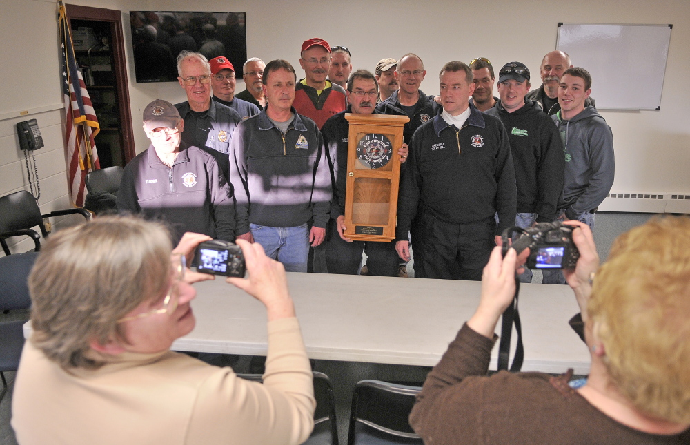 time to leave: Capt. Richard Knight, center, holds a clock given to him for his 35 years of service with the Farmington fire department at the station on Friday.
