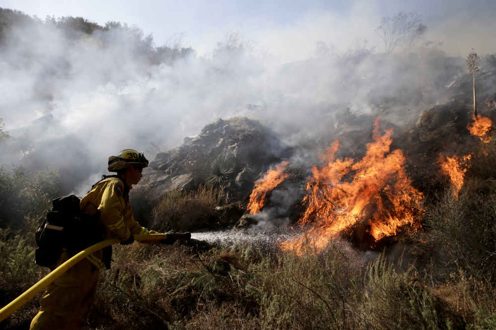 Firefighter Jeff Newby sprays water as he battles the Colby Fire near Azusa, Calif.