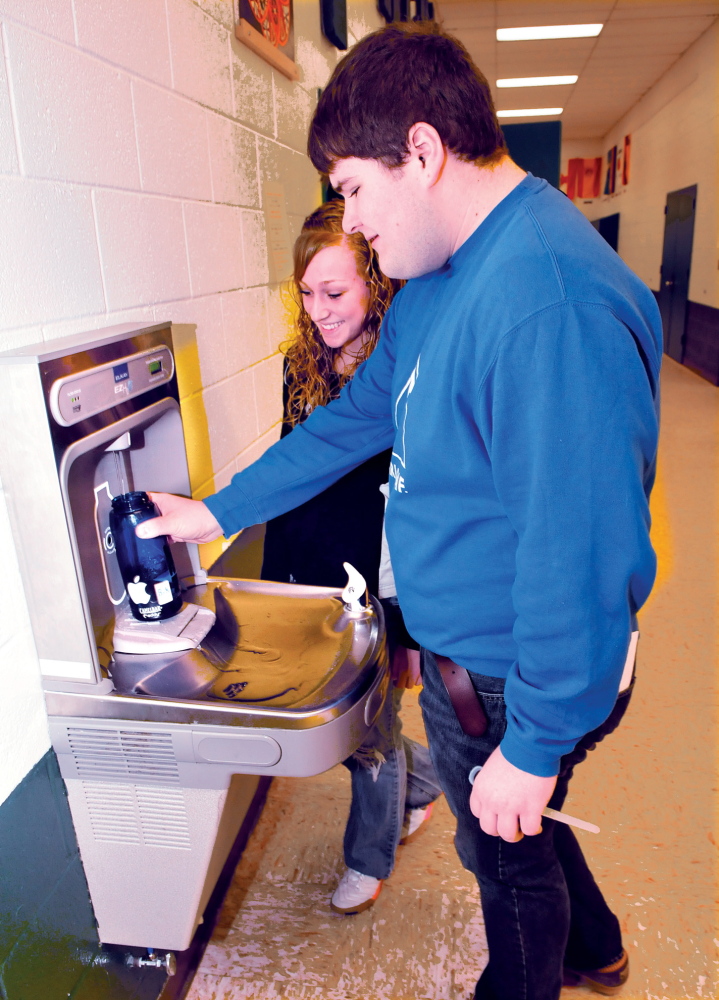 FILL ’ER UP: Carrabec High School students Tyler Pinkham and Skyla Murray fill reusable water bottles Tuesday at a bottle filling station at the Anson school. The students are taking part in an effort to reduce plastic waste.