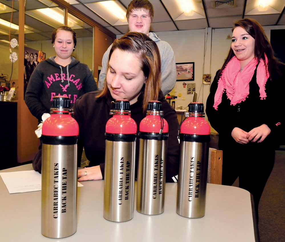 REDUCE AND REUSE: Carrabec High School student Emily Poulin signs a pledge Tuesday to reduce plastic waste by using reusable bottles, foreground. Waiting to sign the pledge, from left, are Taylor Stewart, Jacob Turner and Emily Witham.