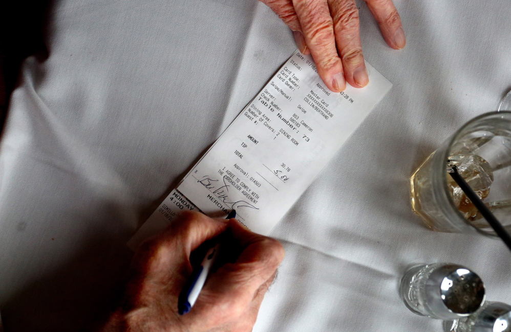 A patron signs his credit card receipt at DiMillo’s. The IRS altered its tax code in 2012 to draw a distinction between voluntary tips and mandatory service charges.