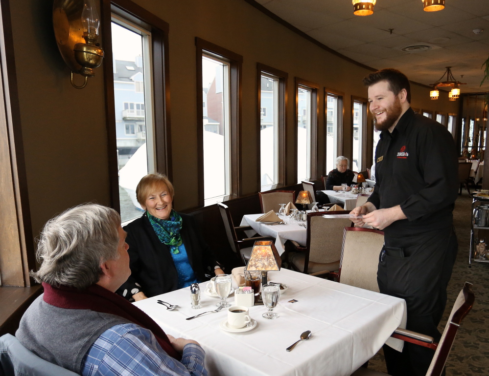 Adam Sousa, a server at DiMillo’s Restaurant, takes the dessert order of Michael Kemna of Cumberland and Sherry Biegel of Gorham after lunch on Thursday. Sousa says he understands the reasoning behind dropping automatic gratuities, but he thinks waitstaff may suffer until guests in large parties become familiar with the need to tip.
