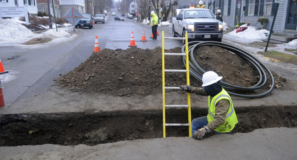 FILLING IN: A contractor installs a distribution line Thursday across Second Street in Hallowell for Summit Natural Gas of Maine. The 2013 arrival of two natural gas companies in the Kennebec Valley has strained the resources of communities and utilities. Summit was connecting a gas line to the building that houses the Liberal Cup.