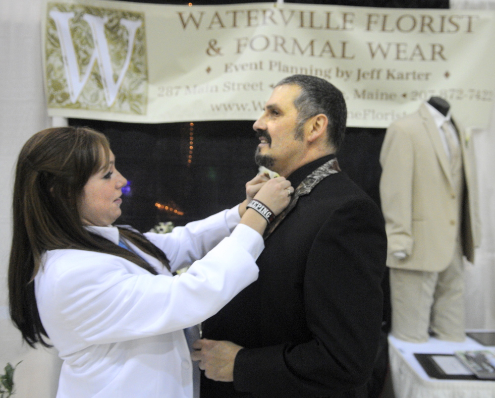 Preparing: Brandy Wyman secures Jeff Karter’s bow tie Sunday at the booth for his business, Waterville Florist & Formal Wear, at the 22nd Annual Augusta Wedding Show at the Augusta Armory.