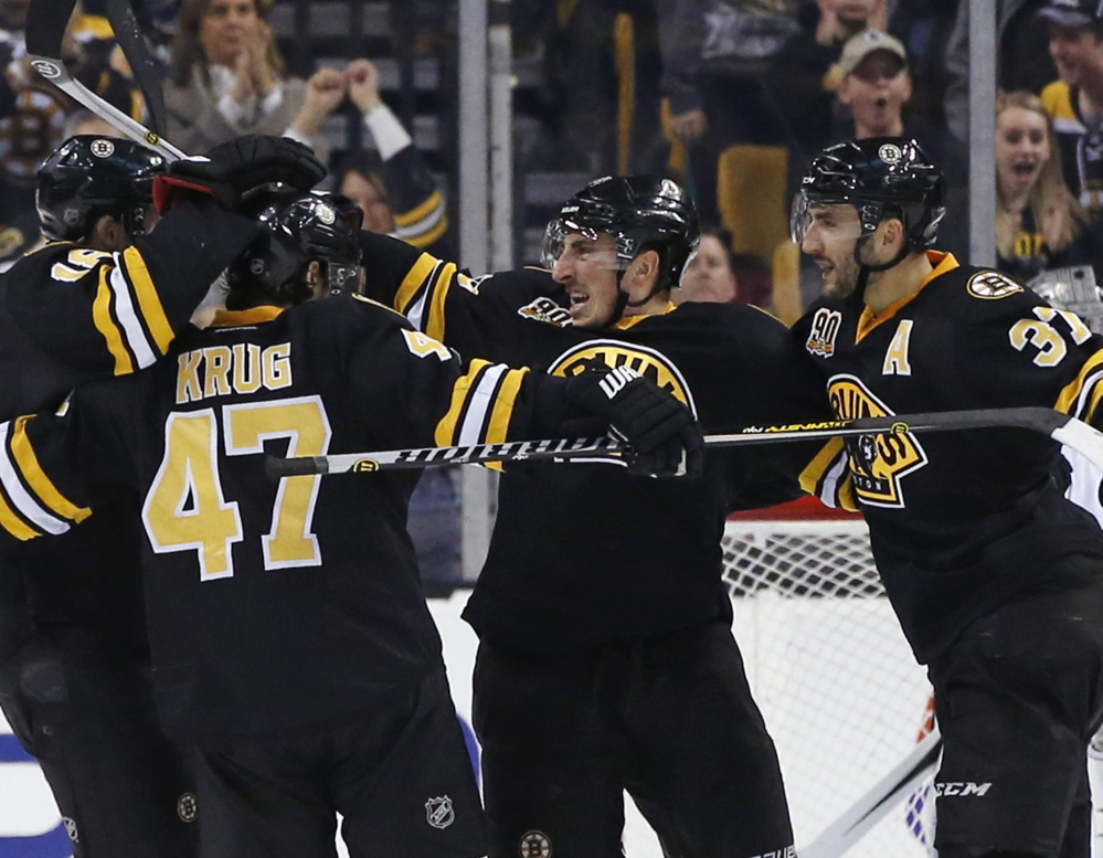 Boston Bruins left wing Brad Marchand, center, celebrates his game-winning goal against the Los Angeles Kings with teammates Torey Krug (47) and Patrice Bergeron (37) during the third period of an NHL hockey game in Boston, Monday, Jan. 20, 2014. The Bruins won 3-2. (AP Photo/Elise Amendola)