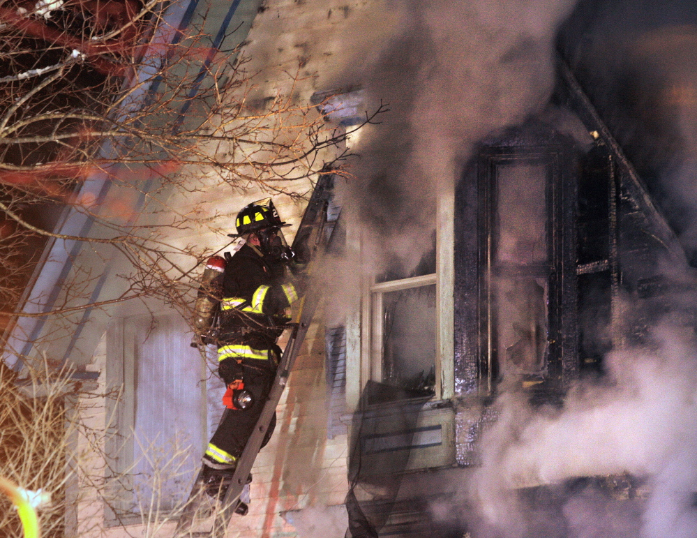 A firefighter battles a fire in an apartment house at 84 Irving St. in Portland Sunday night.