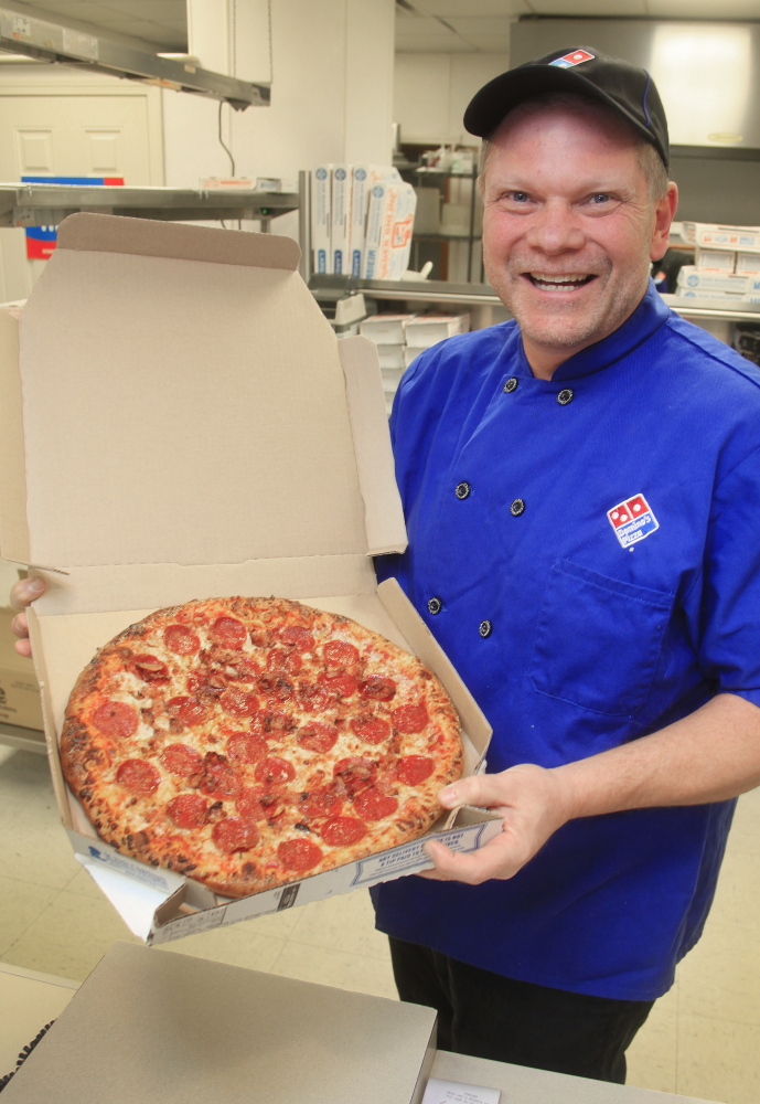 Mike Mullen shows off a fresh pie Monday at his Domino’s pizza store in Standish. Mullen is concerned that pending calorie-labeling rules will be complicated and expensive.