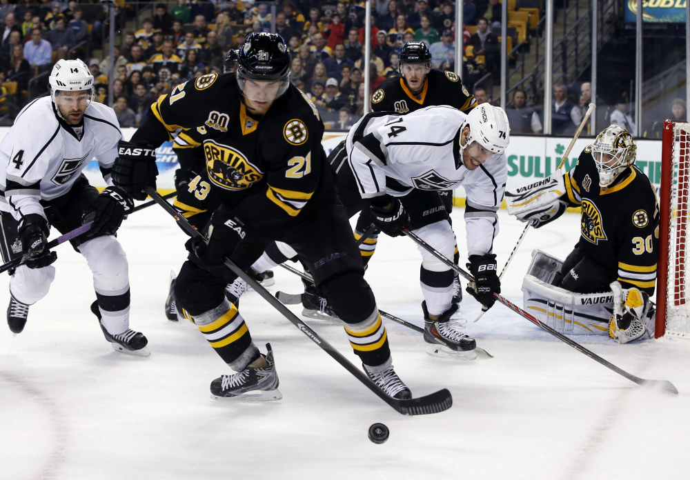 Bruins left wing Loui Eriksson (21) controls the puck against Los Angeles Kings right wing Justin Williams (14) and left wing Dwight King (74) as Bruins goalie Chad Johnson (30) protects the net during the first period in Boston on Monday.