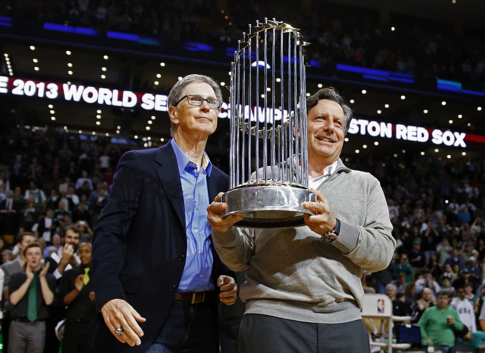 Boston Red Sox owner John Henry, left, and chairman Tom Werner hold the 2013 World Series trophy before an NBA game between the Boston Celtics and the Milwaukee Bucks in Boston on Nov. 1.