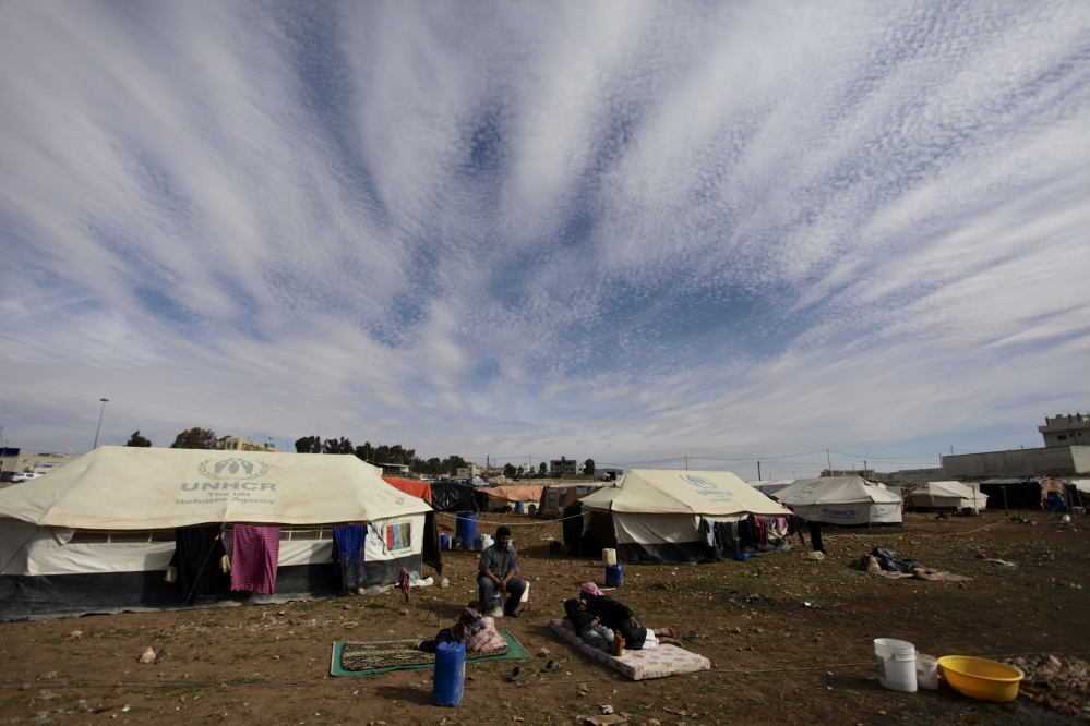 Refugees take a rest outside their tents at an unofficial refugee camp on the outskirts of Amman, Jordan, Wednesday, Jan. 22, 2014. Peace talks intended to carve a path out of Syria’s civil war got off to a rocky start Wednesday.