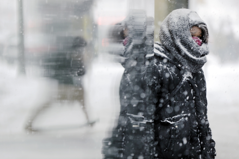 A woman stands at the entrance of a building during a snowstorm Tuesday in Philadelphia.
