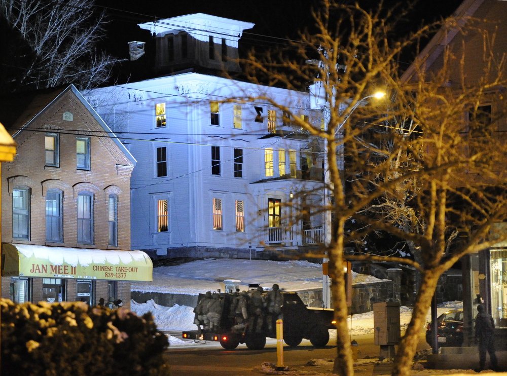 An armored vehicle carrying police tactical team members shines a bright light on the University of Southern Maine fraternity building where an armed student was involved in a standoff Wednesday night in Gorham.